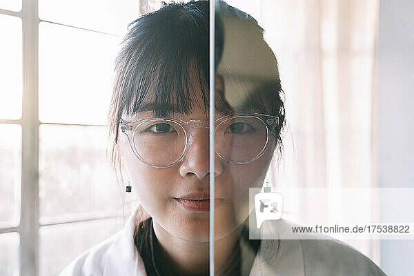 Young scientist behind transparent glass in laboratory