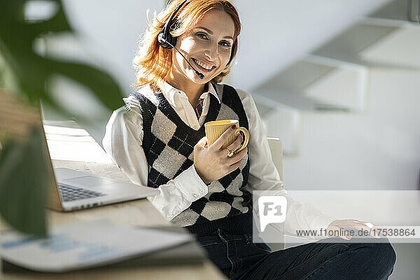 Smiling businesswoman with mug sitting at home office