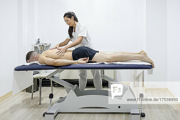 Physical therapist massaging sportsman at rehabilitation center
