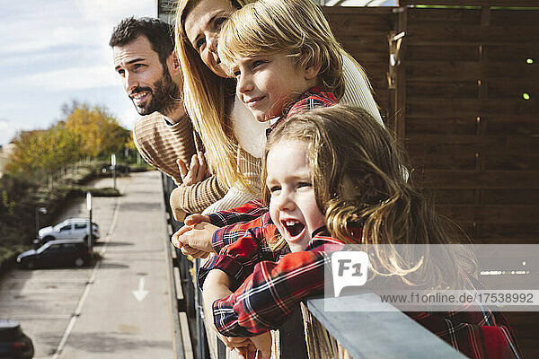 Smiling family leaning on railing in balcony