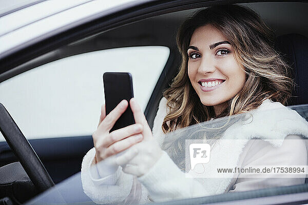 Junge Frau hält Smartphone im Auto
