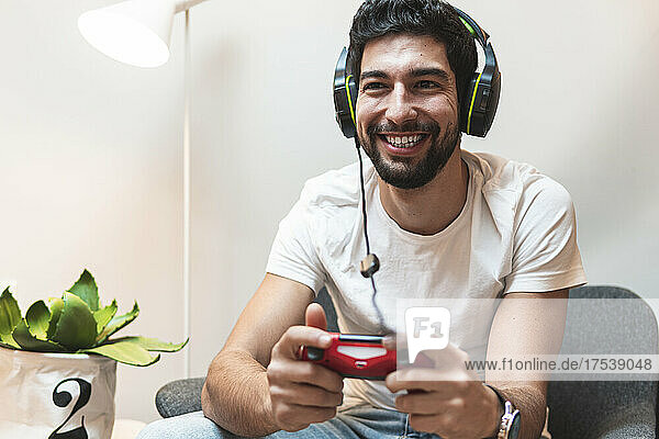 Cheerful man with headphones playing video game at home