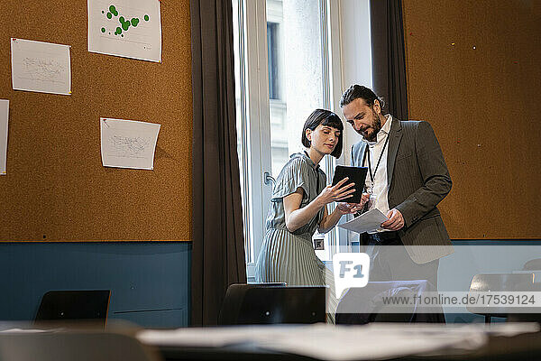 Geschäftsfrau teilt Tablet-PC mit Kollegen im Büro