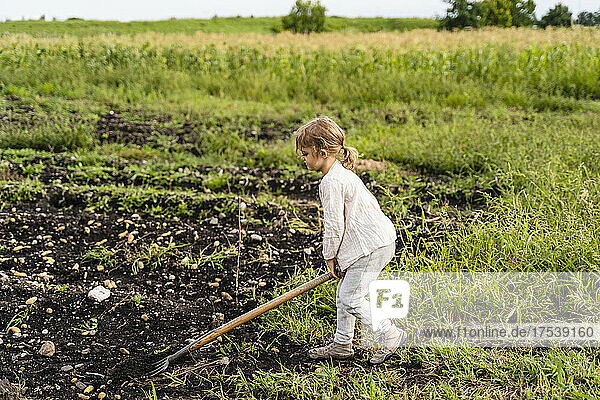 Girl using pitchfork in agricultural field