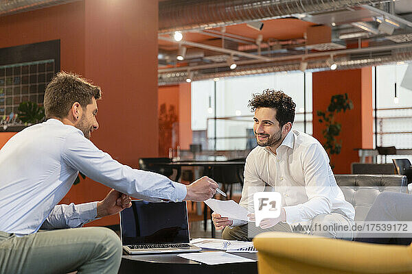 Smiling businessmen discussing document in office