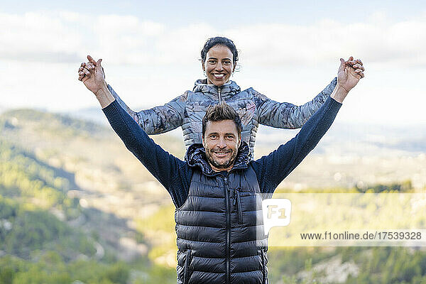 Smiling couple standing with arms outstretched at park
