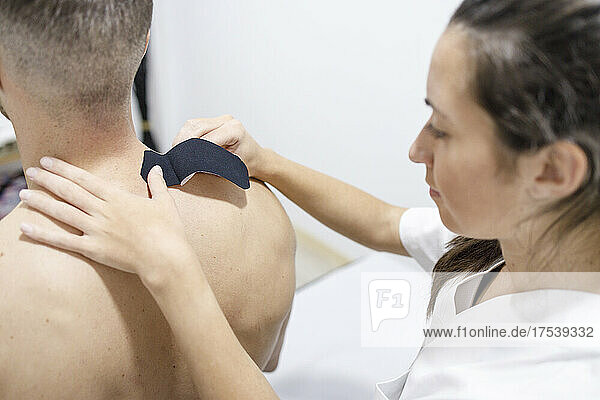 Physical therapist applying therapeutic tape on athlete