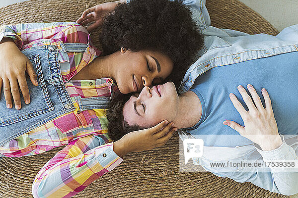 Romantic young couple with closed eyes lying down on carpet
