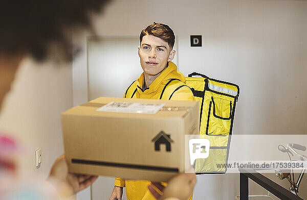 Young man delivering package to woman at doorway