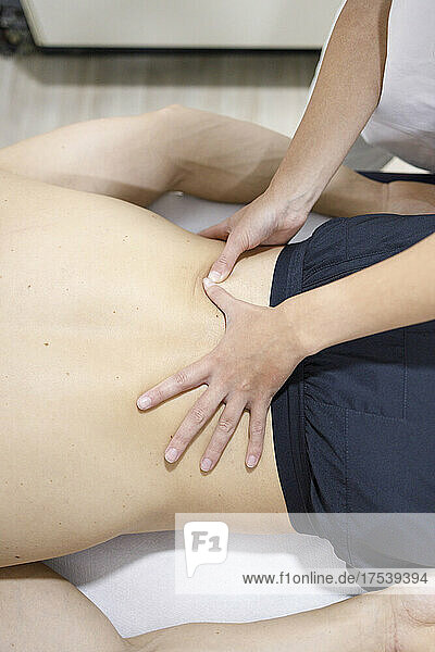 Massage therapist massaging shirtless athlete's back