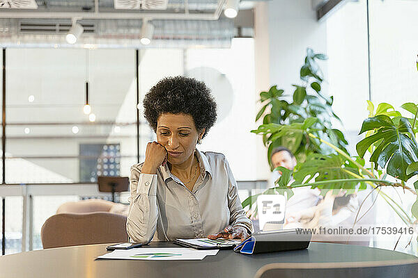 Businesswoman examining document at table in office