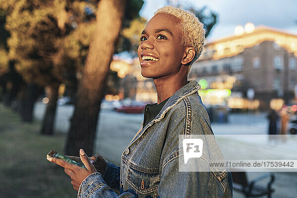 Happy woman in denim jacket holding smart phone