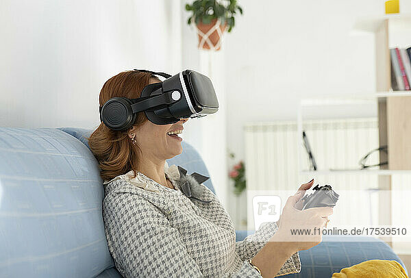 Frau mit Joystick und Virtual-Reality-Headset zu Hause
