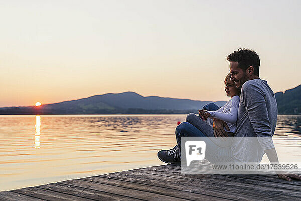 Smiling girl sitting on father's lap by lake  Mondsee  Austria