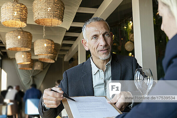Businessman showing contract to client in restaurant