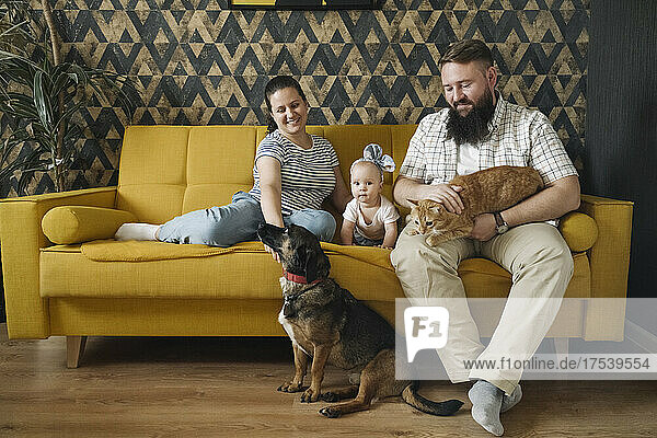 Smiling family with baby girl and pets in living room