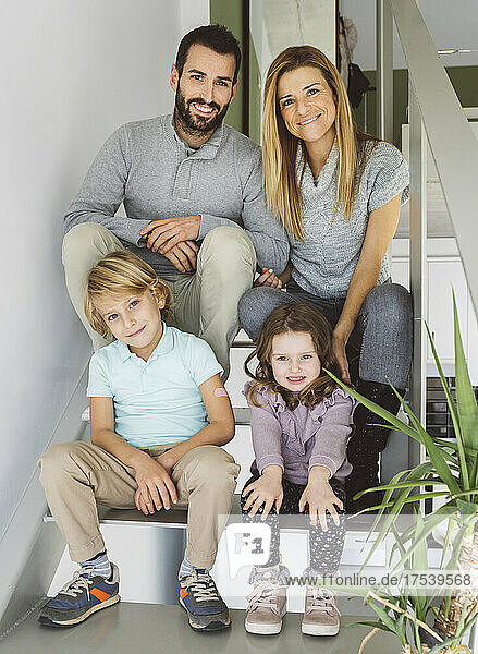 Smiling family sitting on staircase at home