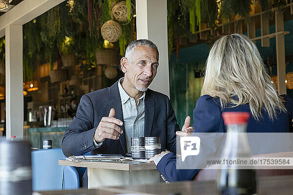Businessman gesturing talking to client in restaurant