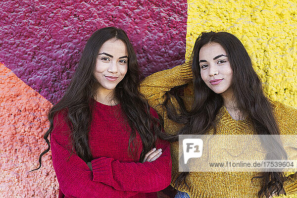 Young sisters smiling in front of colorful wall