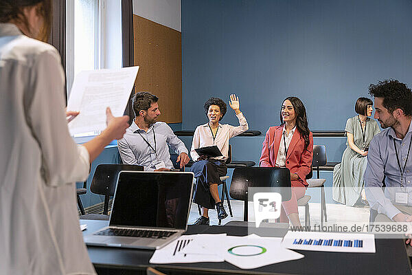 Businesswoman raising hand in meeting at office