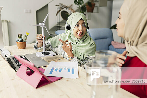 Businesswoman explaining about wind turbine to colleague at home