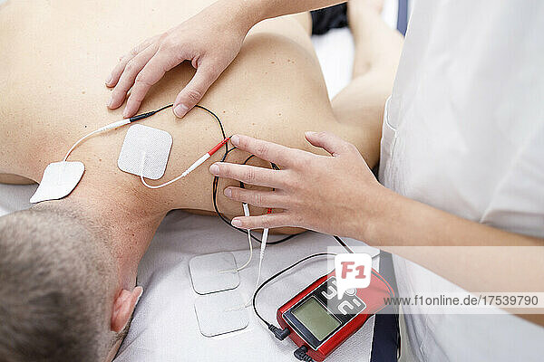Physical therapist applying electrodes on athlete's neck