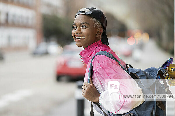 Smiling woman wearing cap carrying backpack