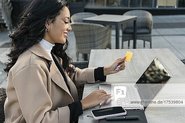 Businesswoman with credit card doing online shopping through laptop