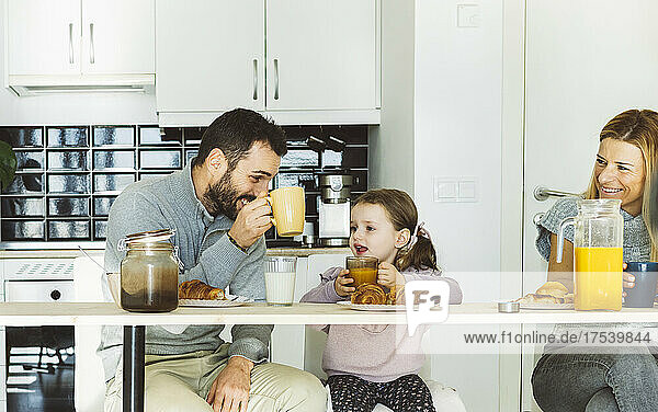 Happy parents having breakfast with daughter at home
