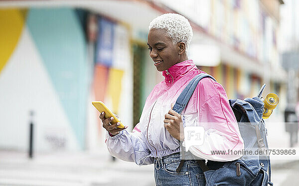 Woman with short blond hair wearing backpack using smart phone