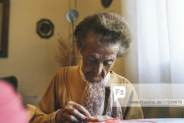 Retired elderly woman knitting at home