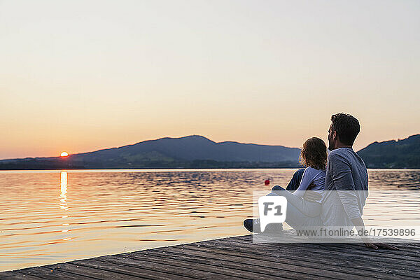 Father and daughter looking at sunset view from jetty  Mondsee  Austria