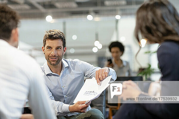 Businessman discussing document with colleagues in office