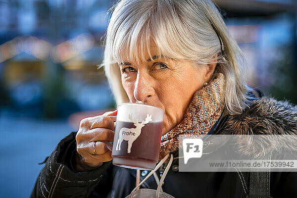 Senior woman drinking mulled wine in winter