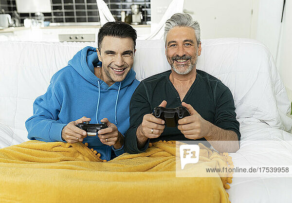 Smiling gay couple playing video game on sofa