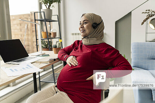 Smiling pregnant businesswoman freelancing at home