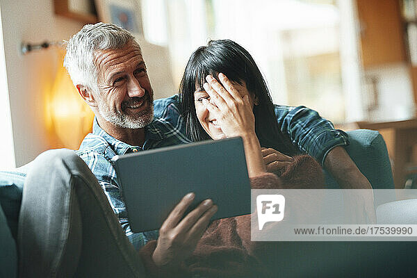 Happy mature couple with tablet PC in living room
