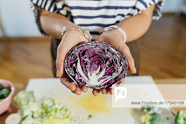 Woman holding halved red cabbage at home