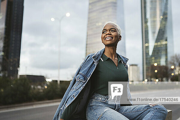 Smiling woman sitting at roadside in city