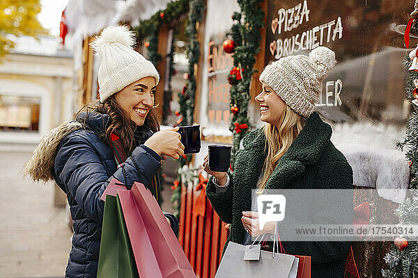 Cheerful friends toasting wine mugs at Christmas Market
