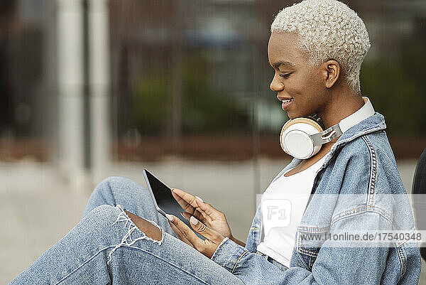 Smiling woman with wireless headphones using tablet PC