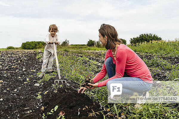 Mother looking at daughter helping harvesting at farm