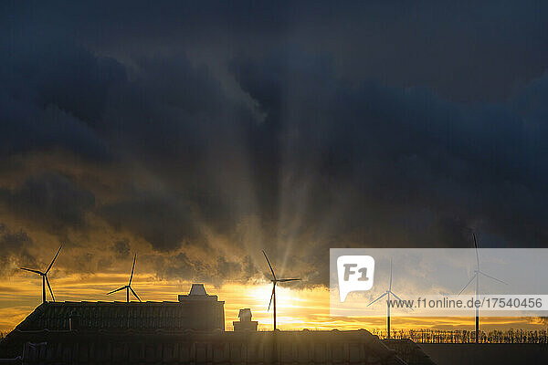 Germany  North Rhine-Westphalia  Grevenbroich  Storm clouds over wind farm at sunrise