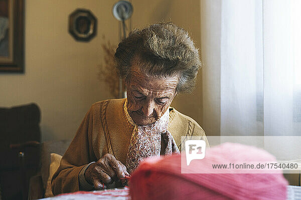 Ältere Frau im Ruhestand strickt am Tisch