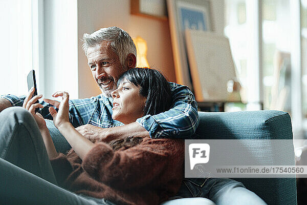 Heterosexual couple using mobile phone in living room