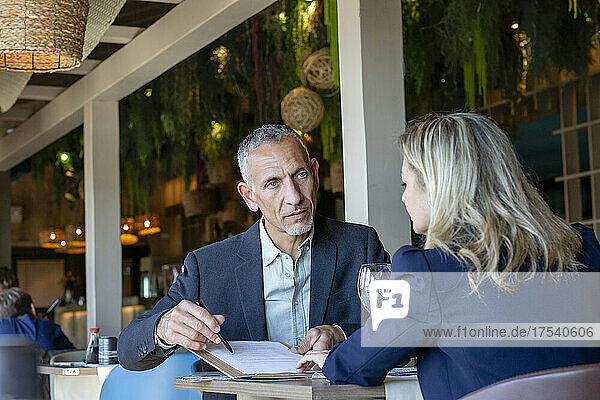 Businessman explaining contract to client sitting in restaurant