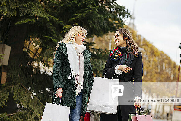 Happy friends holding shopping bags talking with each other