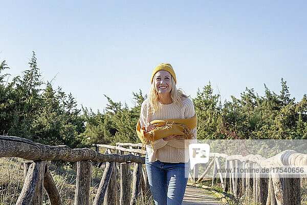 Smiling woman with scarf standing on wooden bridge