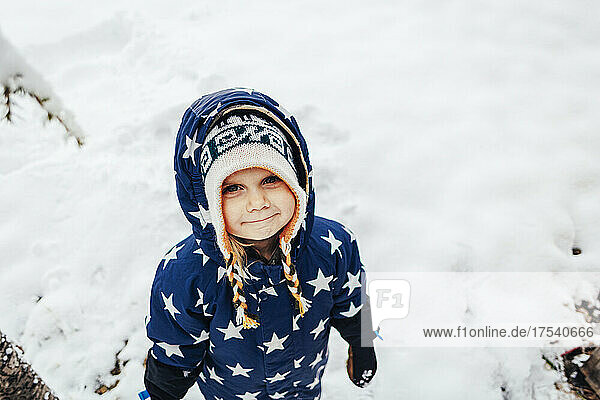 Cute girl wearing warm clothing with star shapes on snow
