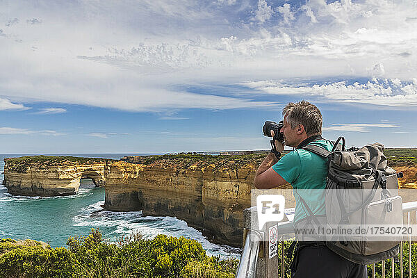 Australia  Victoria  Male tourist photographing natural arch at Loch Ard Gorge
